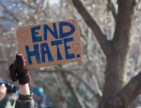Hand holding sign saying "End Hate"