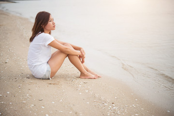Fototapeta na wymiar Young woman with looks lonely feel sit on the beach. Looking awa