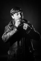 a bearded man in a black leather coat smoking a pipe