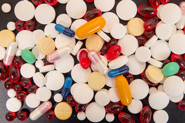 Heap of medicine tablets and pills in blisters on black backgrou