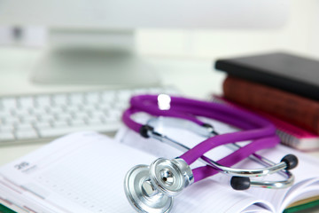 Stethoscope lying on a table an open book