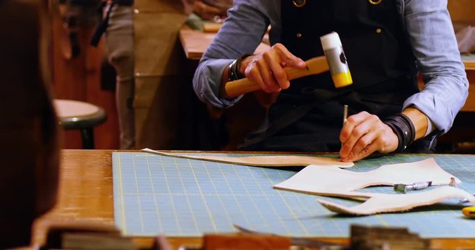 Mid section of craftswoman nailing leather