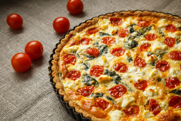 Vegetarian homemade pie, Quiche with tomatoes, spinach and feta cheese.