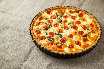 Vegetarian homemade pie, Quiche with tomatoes, spinach and feta cheese.