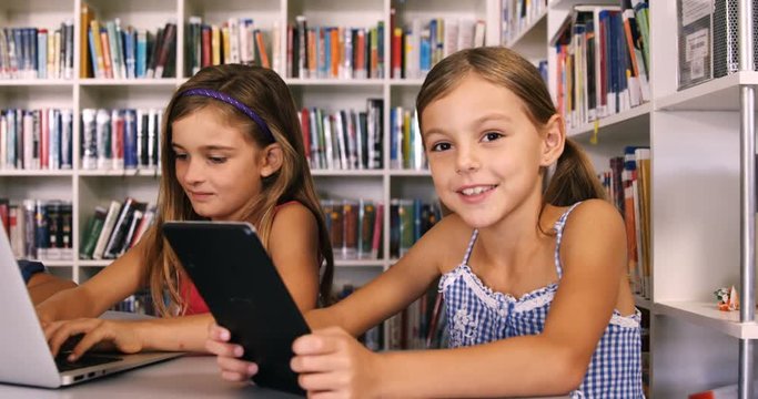 Schoolgirl using digital tablet in library