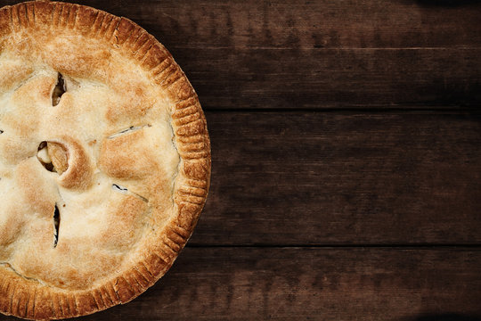 Homemade apple pie dessert shot from overhead over a dark wooden table top with room for copy space.