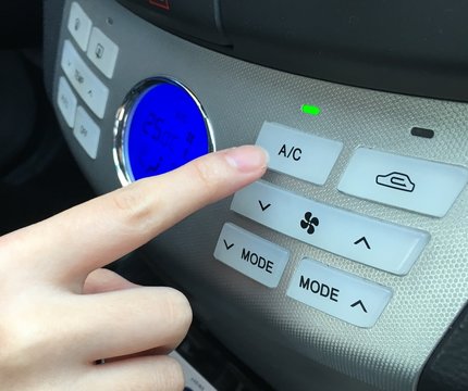Woman turns on air conditioning in a car
