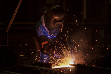 Worker welding steel in car factory 