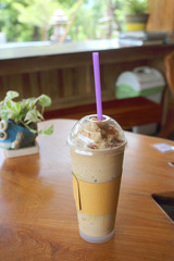 ice fresh coffee in plastic glass on wooden table