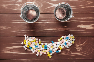 Two empty buckets on wooden background with crumbled tablets