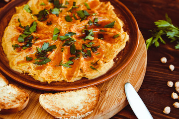 Fresh bowl of homemade hummus with chickpeas, olive oil and parsley. Served with croutons and nuts