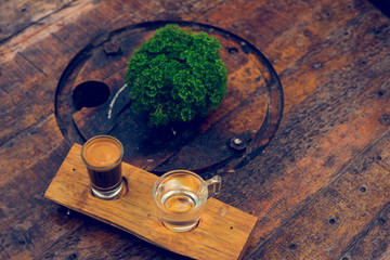 Espresso coffee cup serve with glass of water on wooden table