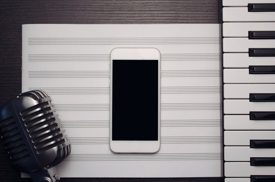 Smart phone, retro microphone, music sheet and music keyboard on