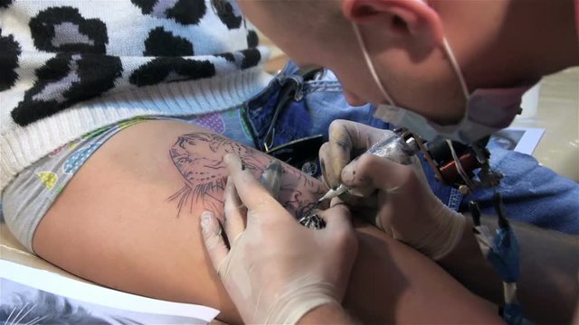Guy fills tattoo on skin. Tattoo parlor. Patterning on skin. Body art