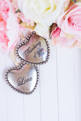Two hearts with fresh pink roses on wooden white background