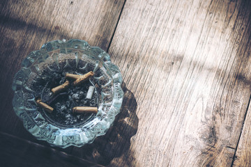 Cigarette stub in a glass ashtray on wooden table background