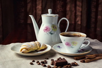 delicious coffee with croissant,a cup of coffee and croissants with coffee beans and cinnamon sticks,breakfast with cup of coffee, croissants and chocolate