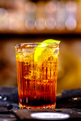 Brown cocktail with a slice of lemon poured into a faceted glass