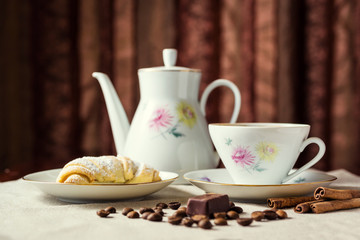 delicious coffee with croissant,a cup of coffee and croissants with coffee beans and cinnamon sticks,breakfast with cup of coffee, croissants and chocolate