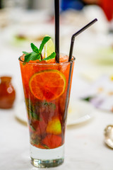Red cocktail with lime fruits and mint in the glass.