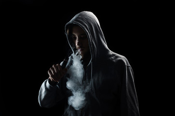 One man in the hood vaping e-cigarette and blowing a cloud.