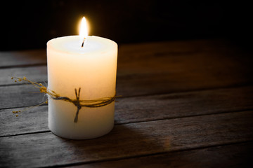 Fototapeta na wymiar Large white burning candle on aged wood background, tranquility concept, contemplation,meditation