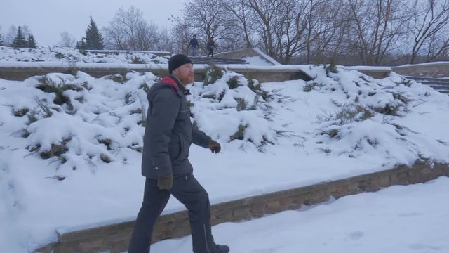 a Bearded Man Going Down a Snowy Winter Staircase, and Moving to Artyom Monument of 1927, Which is Twenty Meters High in the Evening Twilights