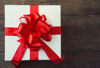 gift box with red bow on wood table.