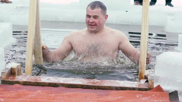Young man having recreational swim in the ice hole