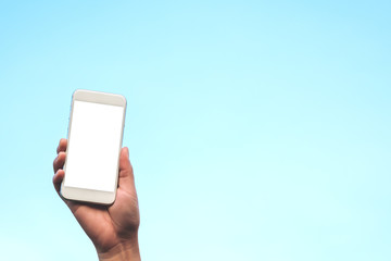 Mockup image of hand holding white mobile phone with blank white screen in blue sky background