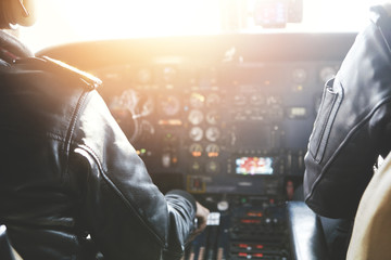 People, occupation and aerospace concept. Captain and copilot wearing headset and outfit flying...