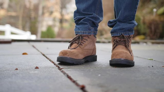 A slow motion shot of a construction worker dropping a lead pipe on his steel toed boots.  	