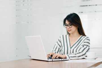 Happy beautiful young Asian woman smile while working with laptop