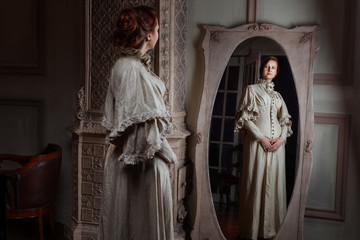 Woman in retro style noblewoman standing in front of the mirror trying on a dress.