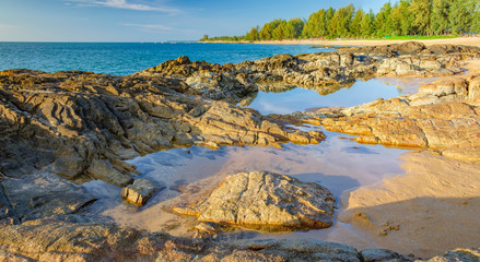 Fototapeta na wymiar Beautiful seascape with sea, rock and a strip of white sand of Nang Thong Beach, Khao Lak, Thailand. View of bright blue sea with protruding stones. Nature composition.
