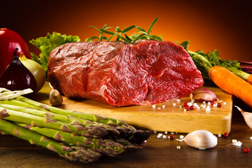 Fresh raw beef on cutting board and vegetables 