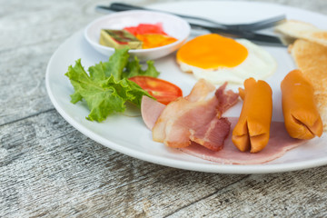 Breakfast set with bacon ,sausages and fried egg on white dish
