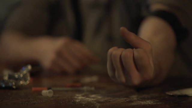 Hand of depressed man making drug injection with syringe at abandoned place