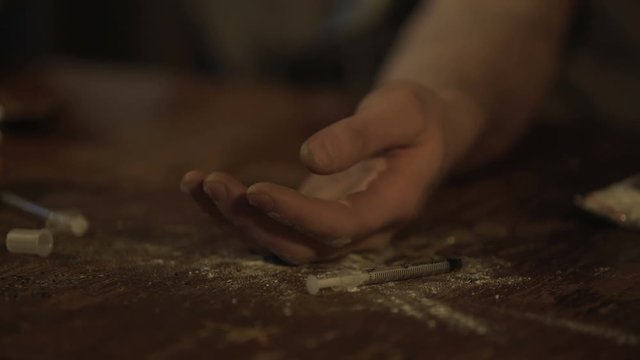 Hand of male opiate addict under influence falling on table, drug abuse problem