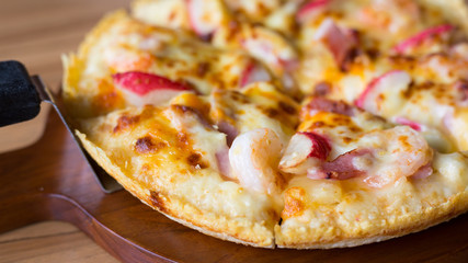 Close up of delicious fresh pizza with seafood on wooden table