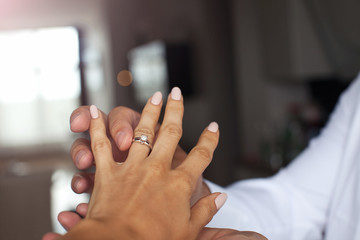 Close up of man putting ring to his woman finger.