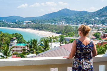 Fototapeta na wymiar Woman enjoying the views over Kata beach from the hotel balcony. Phuket, Thailand