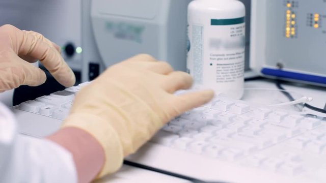 Hands scientist scoring data to a computer in laboratory