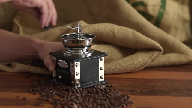 Kaffebohnen von Hand gemahlen, retro Kaffem&uuml;hle mit Kaffeebohnen und Jutesack