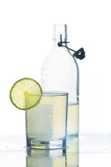 Glass and bottle of cold citrus beverage