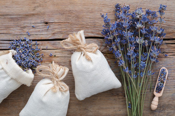 Dry lavender flowers and sachets on wooden background. Top view.