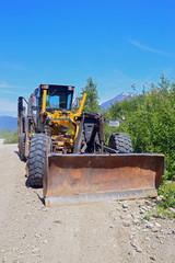 Grader on dusty gravel road