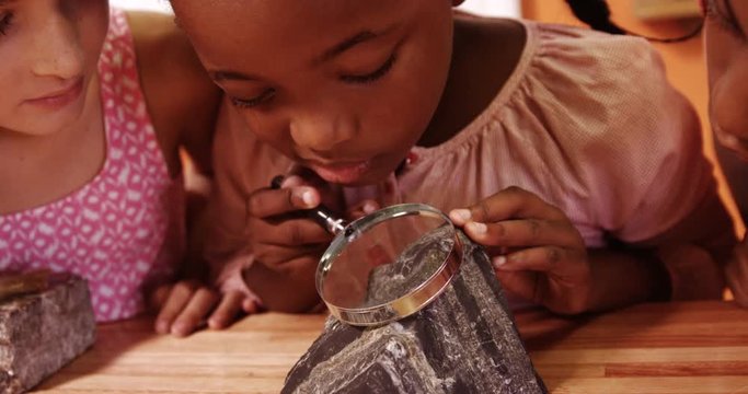 School kids using magnifying glass over rock