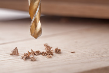 Obraz na płótnie Canvas metal drill bit make holes in wooden oaks plank