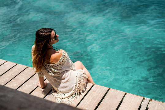Relaxed beautiful young woman sunbathing on the pier.
